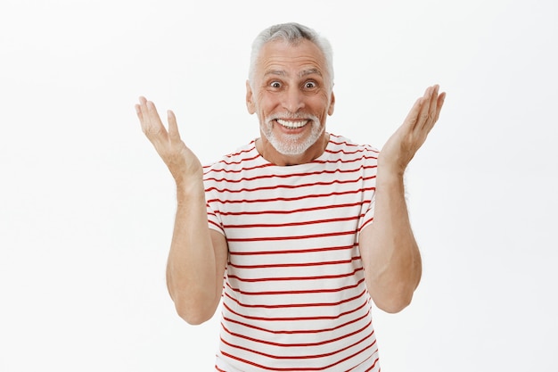 Verrast gelukkig senior man reageert op geweldig nieuws, vrolijk lachend