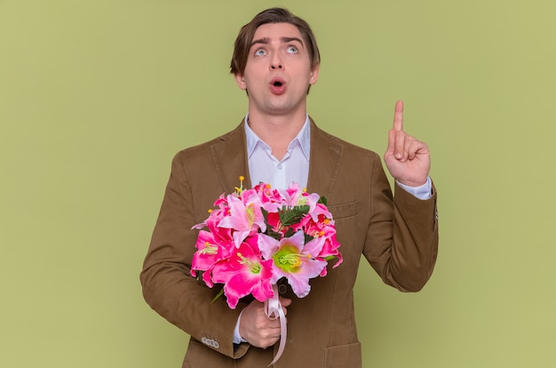 Verrast jonge man met boeket bloemen opzoeken verbaasd wijzen