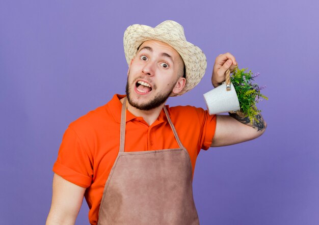 Verrast mannelijke tuinman met tuinhoed houdt bloempot vast