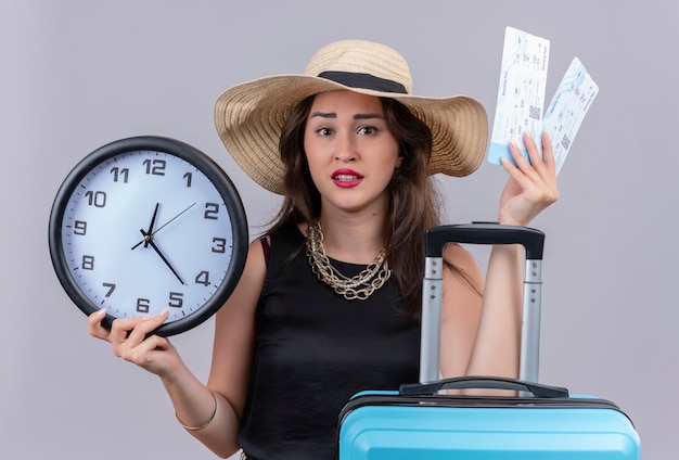 Verrast reiziger jong meisje draagt zwarte onderhemd in hoed met koffer en kaartjes op witte achtergrond