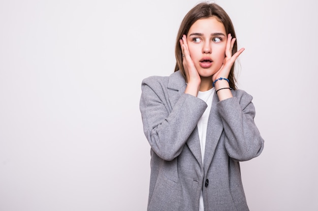 Verraste gelukkige mooie vrouw in opwinding die over witte achtergrond wordt geïsoleerd