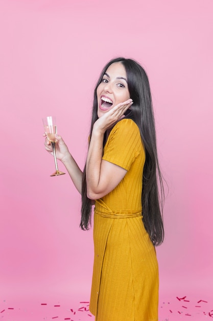 Verraste jonge vrouw met wijnglas op roze achtergrond