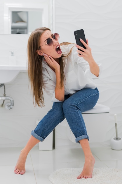 Gratis foto verraste vrouw die haar telefoon bekijkt