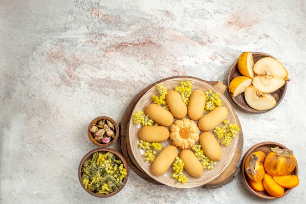 Verre schot van een bord met koekjes op een houten schaal en kommen met fruit en droge bloemen eromheen