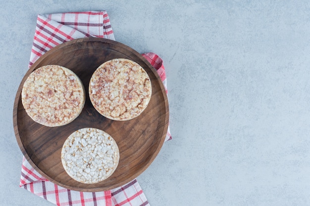 Verrukkelijke gepofte rijstwafels op dienblad op handdoek op marmer.