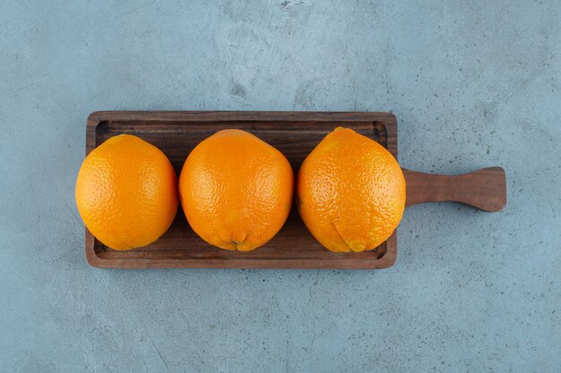 Verrukkelijke sinaasappelen op een bord, op de marmeren achtergrond.