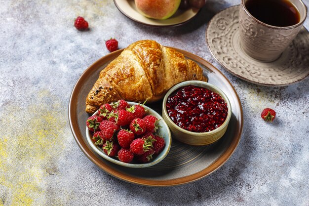 Vers gebakken croissants met frambozenjam en frambozenfruit.