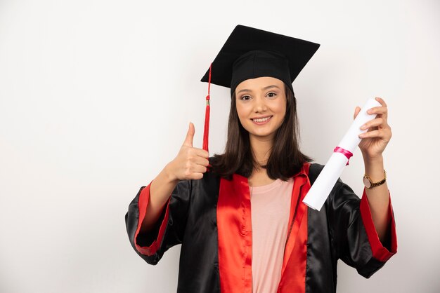 Vers gediplomeerd wijfje dat met diploma duimen op witte achtergrond maakt.