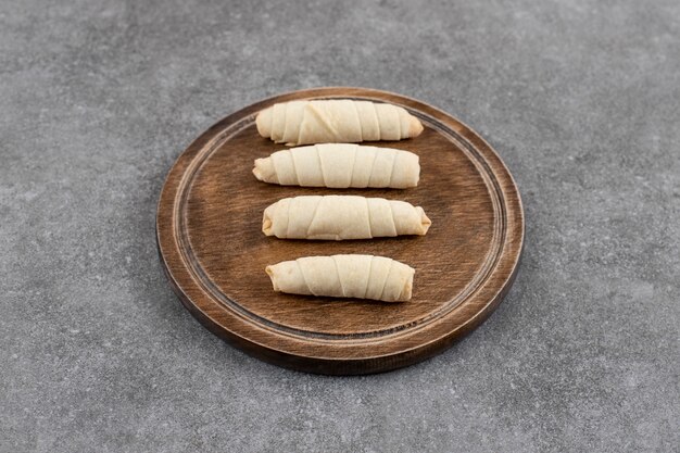 Vers gerolde zelfgemaakte koekjes op een houten bord.