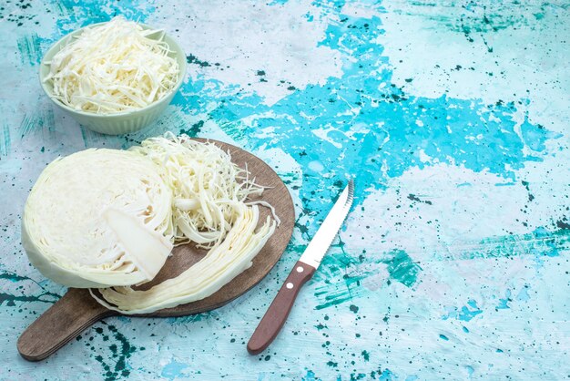 vers gesneden kool met halve hele groente op helderblauw bureau, plantaardige maaltijd snack gezonde salade