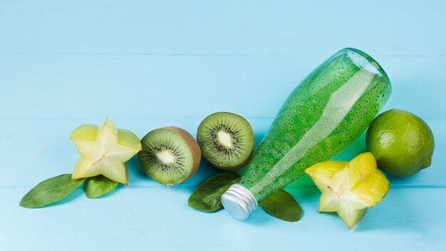 Vers groen fruit en fles op blauwe achtergrond