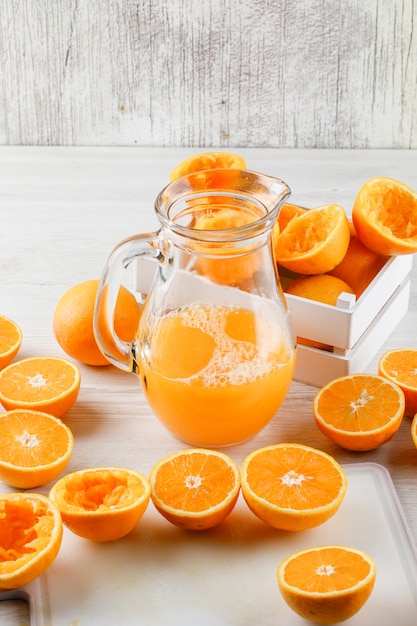 Vers jus d'orange in een kruik met sinaasappelen, de scherpe mening van de raads hoge hoek over houten oppervlakte