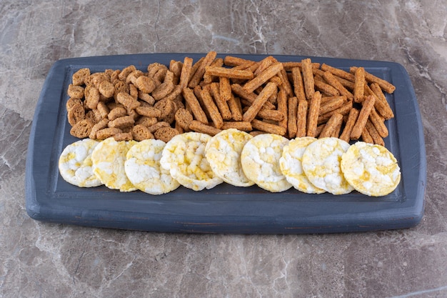 Verscheidenheid aan knapperige crackers op donkere plaat. Hoge kwaliteit foto