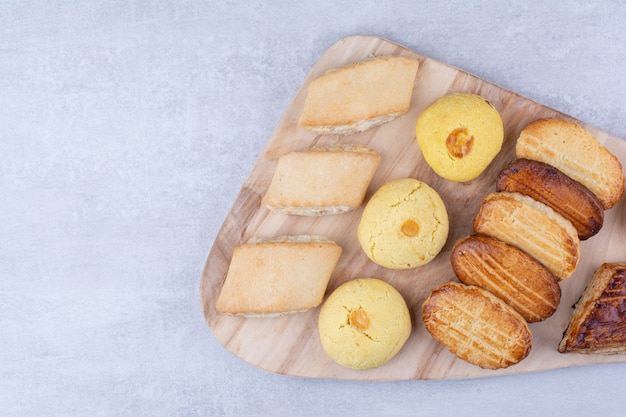 Verscheidenheid aan smakelijke koekjes op een houten bord.