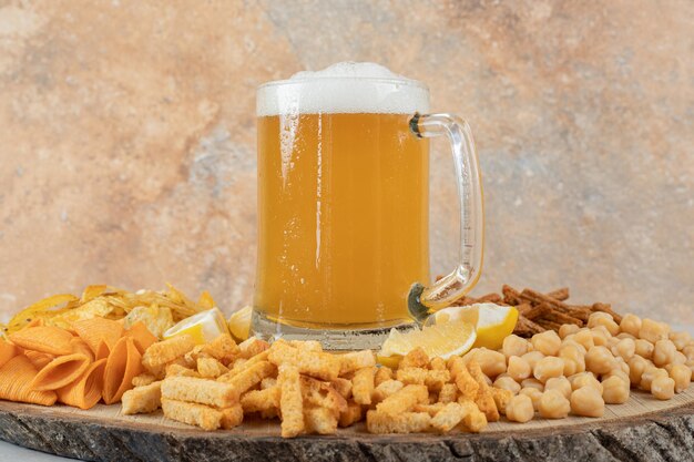 Verscheidenheid aan snacks en glas bier op houten stuk