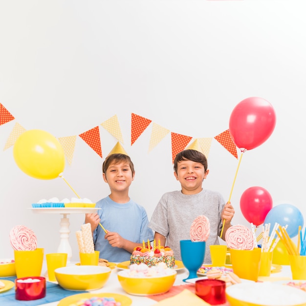 Verscheidenheid van voedsel op tafel met twee jongens houden van ballonnen in feest