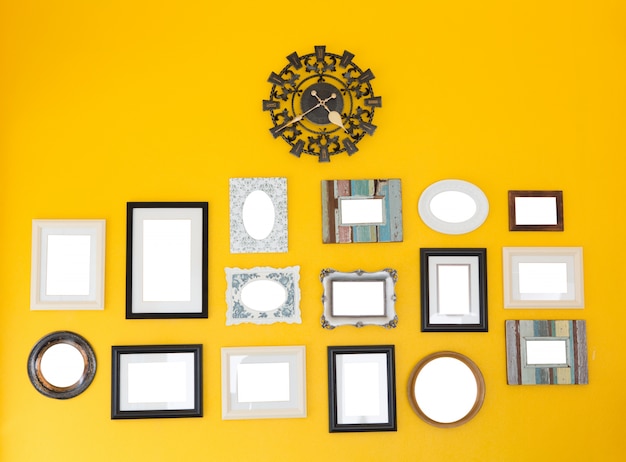 Gratis foto verschillende frames met uitstekende klok op de gele muur
