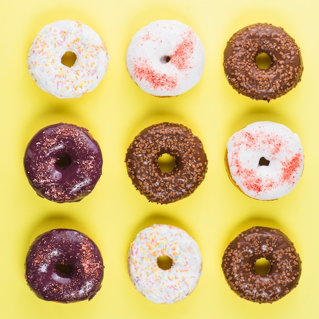 Verschillende kleurrijke berijpte donuts op gele achtergrond