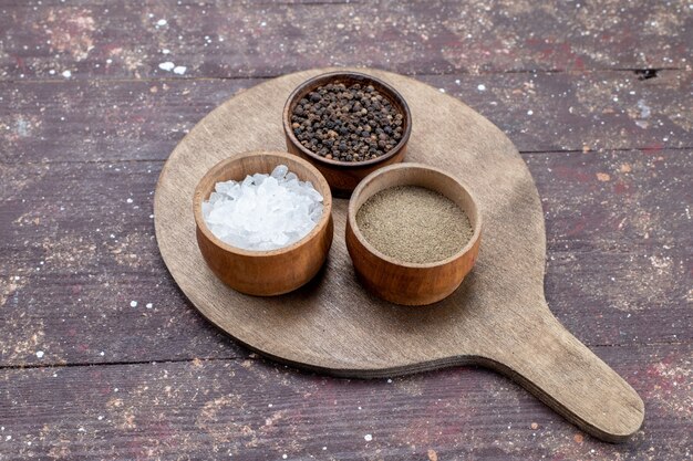 verschillende kruiden zout peper in bruine kommen op bruin houten rustiek bureau