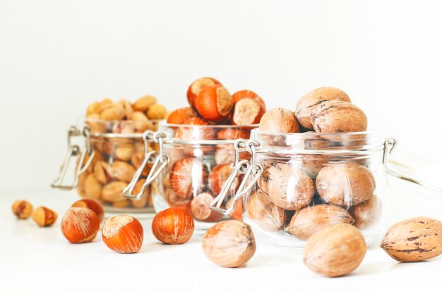 Verschillende noten selectie: hazelnoten, pistache en pecannoten in glazen potten