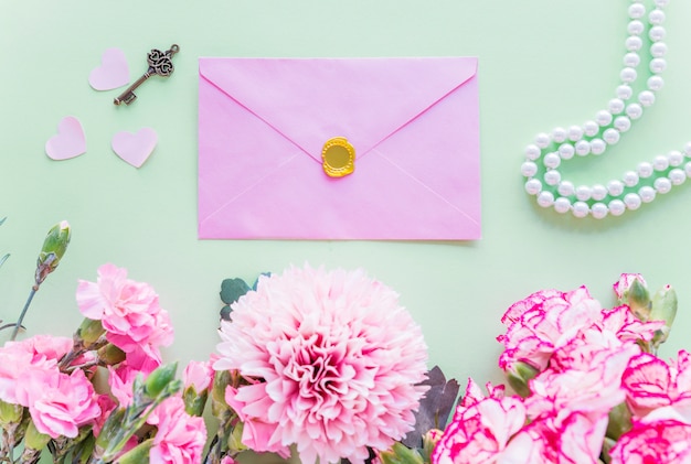 Verschillende roze bloemen met envelop op groene lijst