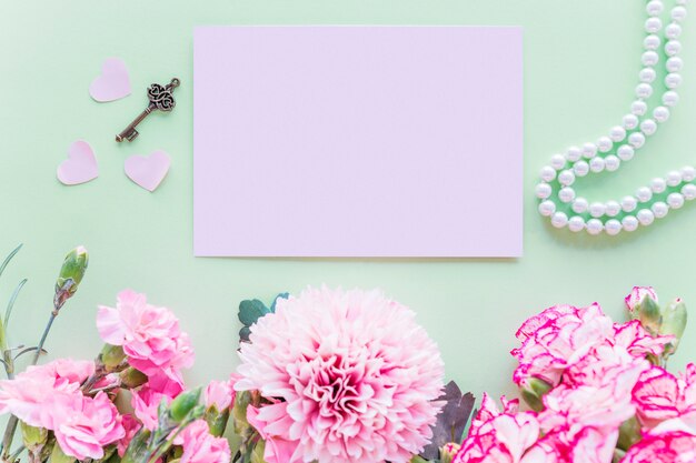 Verschillende roze bloemen met papier op groene tafel