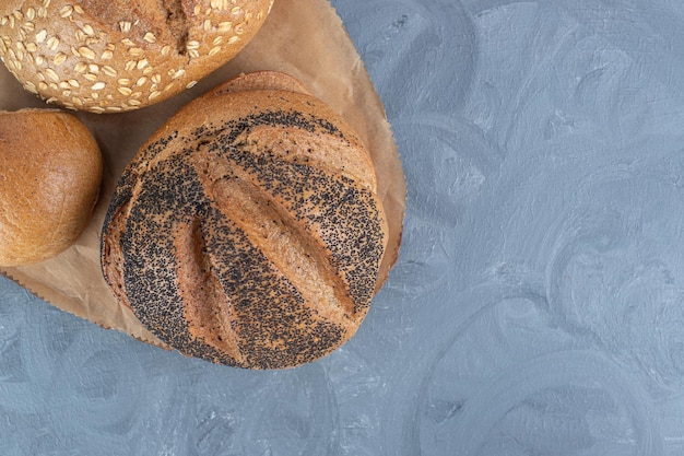 Verschillende soorten brood gebundeld op een houten bord op marmeren tafel.