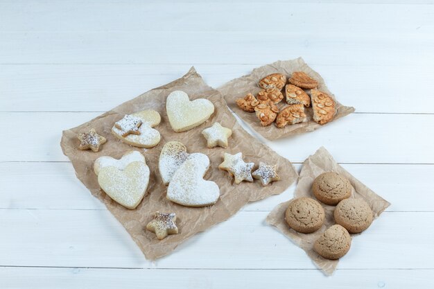 Verschillende soorten koekjes op stukken van zakken op een witte houten raadsachtergrond. plat leggen.