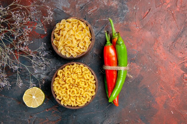 Verschillende soorten ongekookte pasta's cayennepeper in verschillende kleuren en maten in elkaar gebonden met touw op gemengde kleur achtergrond