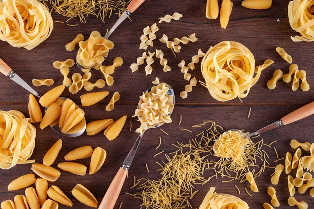 verschillende soorten pasta in lepels op houten tafel