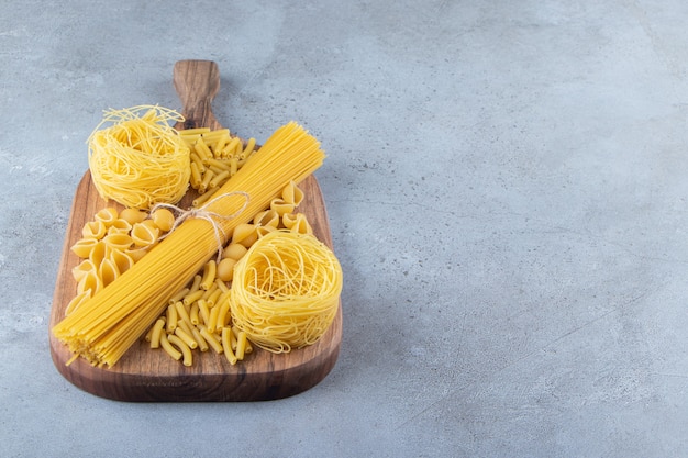 Verschillende soorten rauwe droge pasta op een stenen achtergrond.