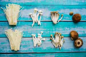 Gratis foto verschillende soorten rauwe gezonde champignons gerangschikt over oude houten tafel