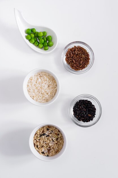 Verschillende soorten rijst met groene bonen in kommen op tafel