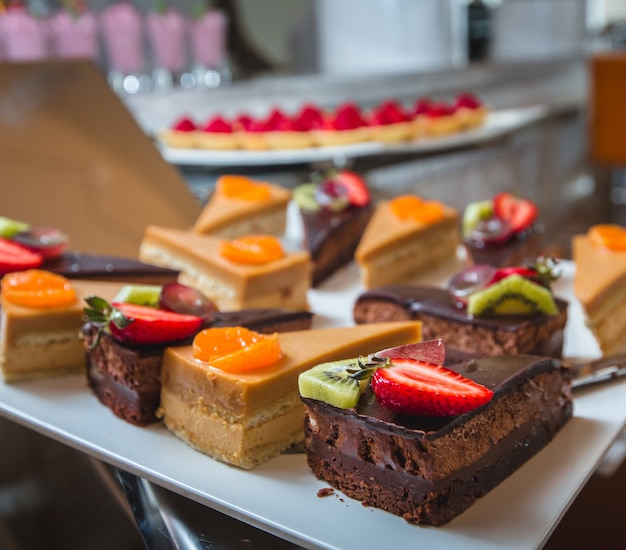 Gratis foto verschillende soorten room-, karamel- en chocoladetaarten met fruit bovenop