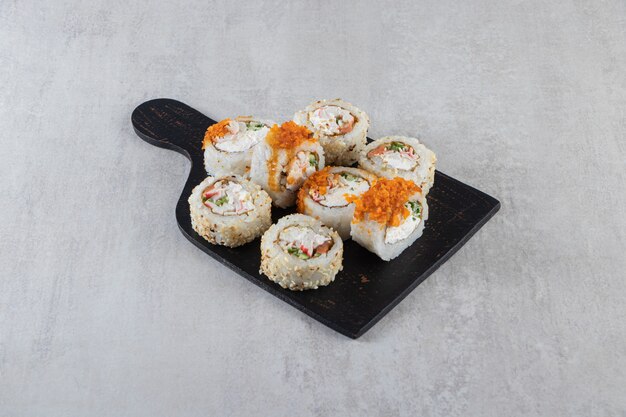 Verschillende soorten sushi rollen op een houten bord geplaatst.