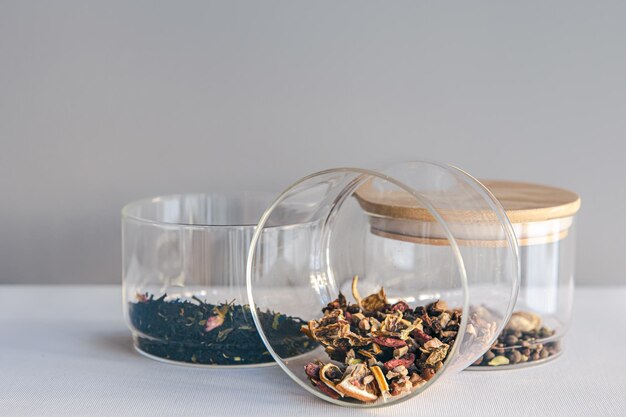 Verschillende soorten thee in glazen potten op een lichte achtergrond geïsoleerd