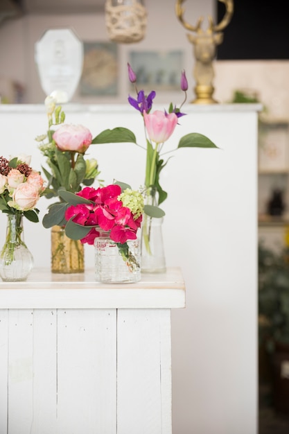 Verschillende soorten vazen met kleurrijke bloemen op tafel in de winkel van de bloemist