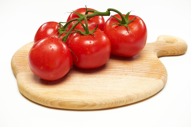 Verschillende tomaten liggen op een houten snijplank. Geïsoleerd op een witte achtergrond.