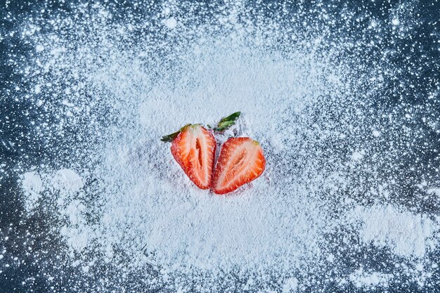 Verse aardbeiplakken op blauw oppervlak met poeder