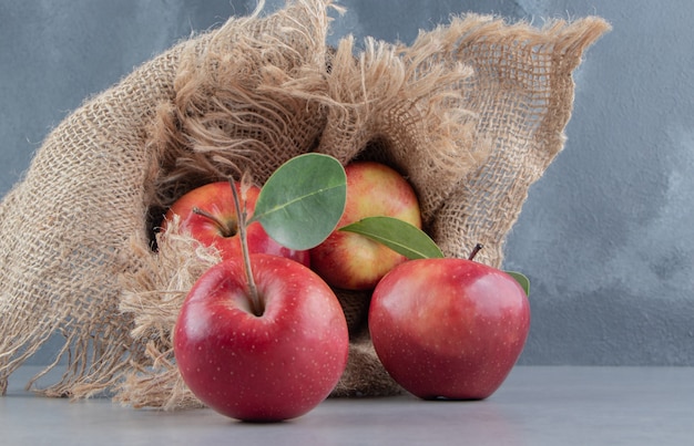 Verse appels die uit een met doek bedekte mand op marmer morsen.