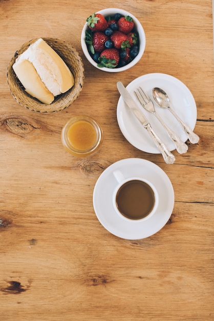 Verse bessen; brood; jam en koffiekopje op houten gestructureerde achtergrond