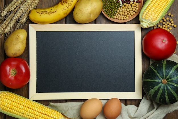 Verse biologische groenten, fruit, eieren, bonen en corns met bord op vintage houten tafel