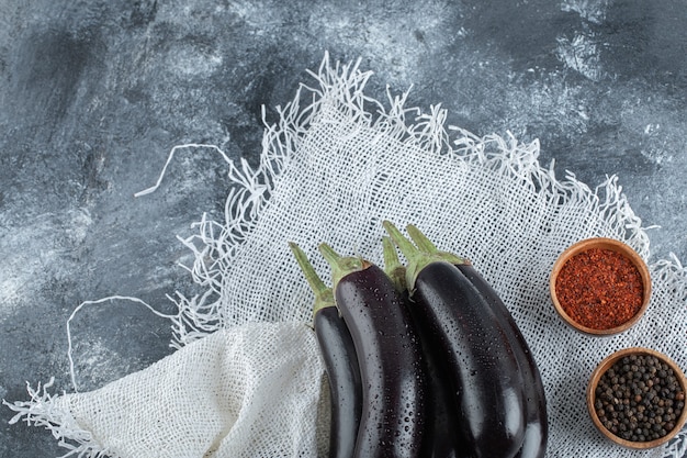 Verse biologische paarse aubergines met kruiden, rode en zwarte peper.