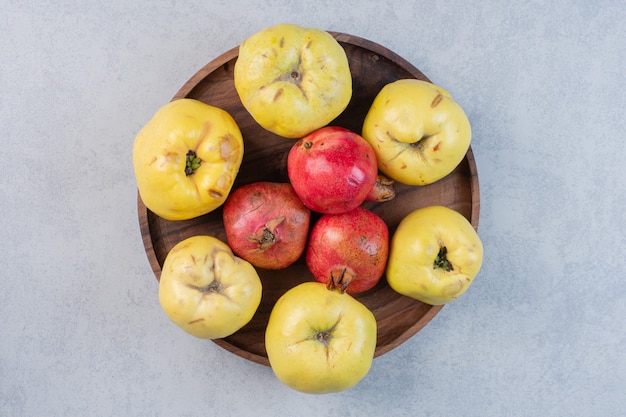 Verse en biologische appelkweepeer en granaatappel op een houten bord.