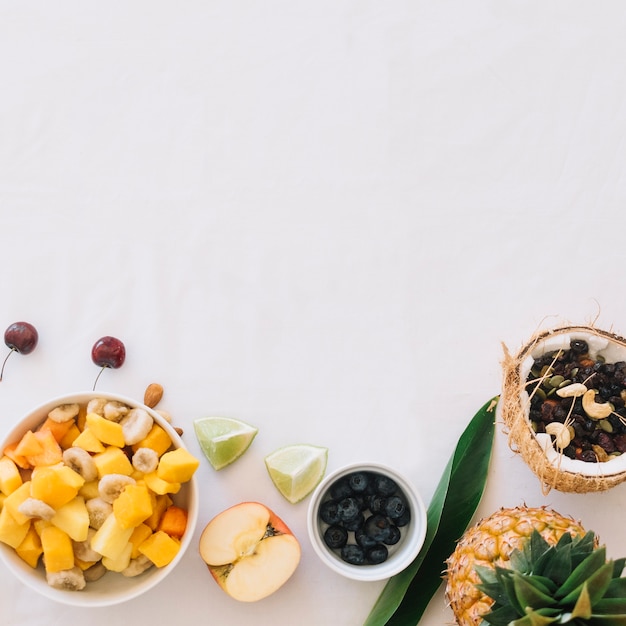 Verse fruitsalade met dryfruits in de kokosnoot die over witte achtergrond wordt geïsoleerd