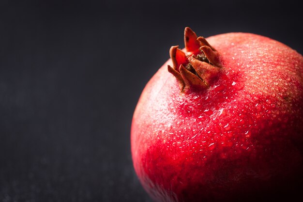 Verse granaatappel met water druppels op een donkere achtergrond