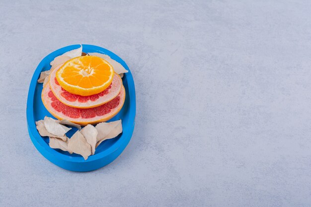 Verse grapefruit, citroen en sinaasappelringen op blauw bord.