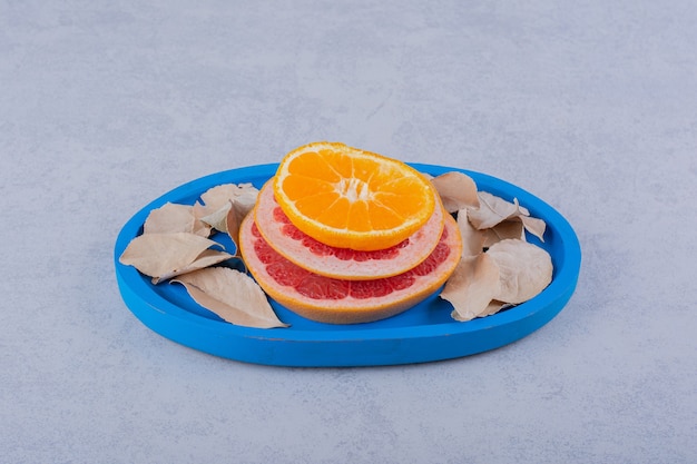 Verse grapefruit, citroen en sinaasappelringen op blauw bord.