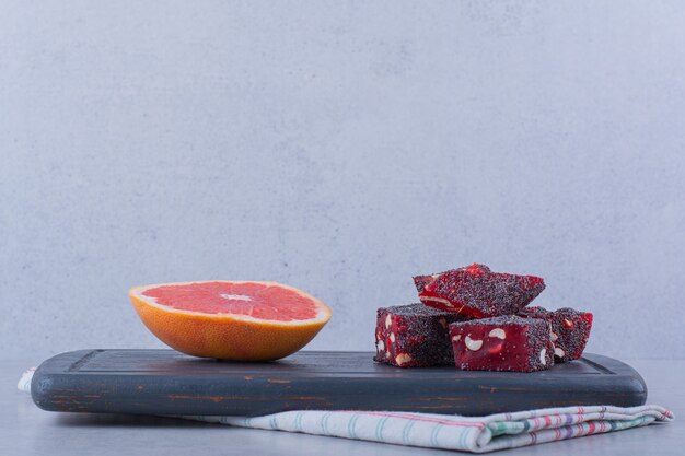 Gratis foto verse grapefruit slice en smakelijke oosterse zoetigheden op donker bord.