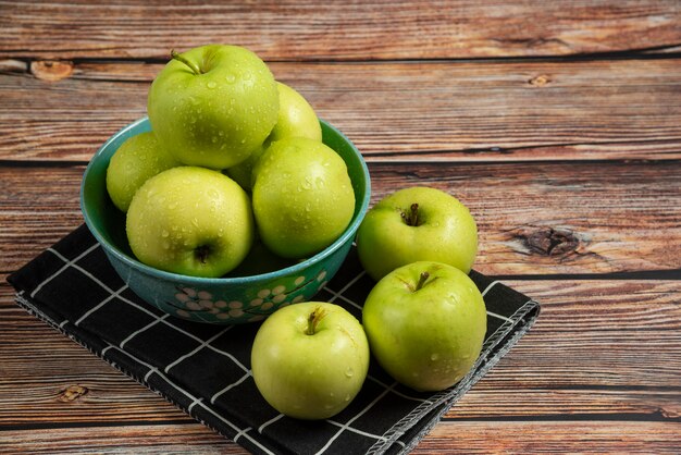 Verse groene appels met waterdruppels erop in een blauwe kom, bovenaanzicht